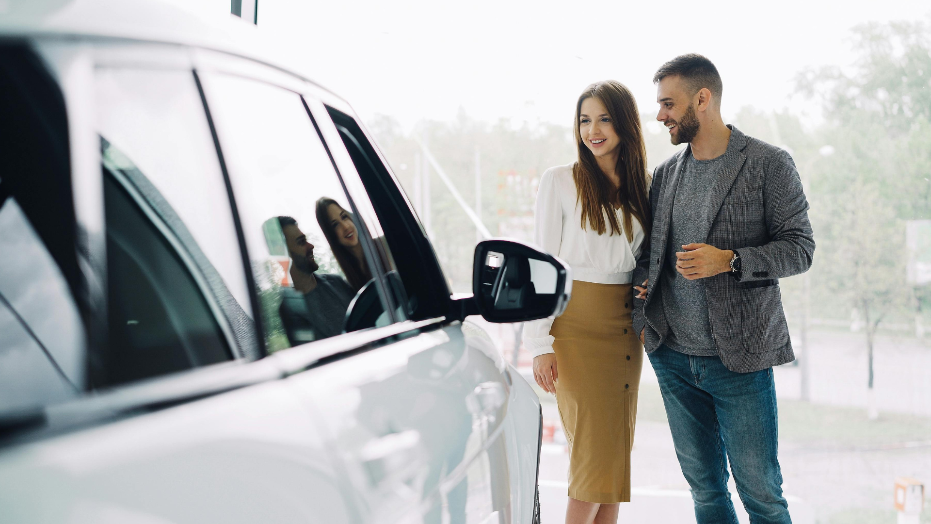 A couple admiring a new car at a dealership showroom